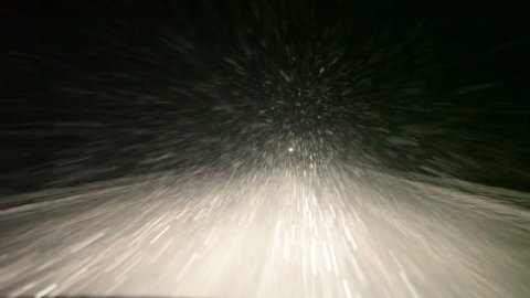 Night road with strong blizzard in moving car headlight, winter, pov, loop. Northern Russia