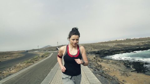 Young woman with smartwatch jogging by sea, slow motion shot at 240fps
