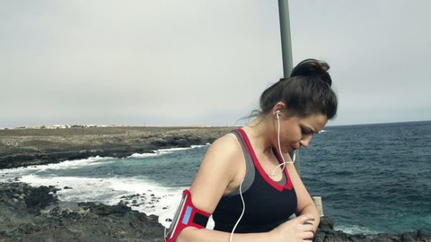 Young female jogger with smartwatch checking pulse by sea, slow motion shot at 240fps
