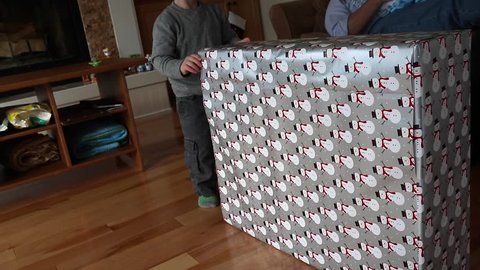 A toddler unwraps a Christmas present in the living room