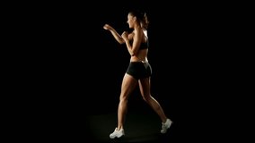 Young athletic woman wearing sporstwear is exercising throwing punches - slow-motion isolated-on-black HD video footage