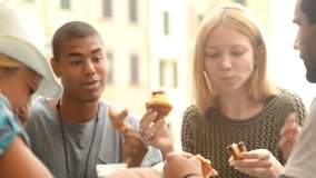 Four multiethnic friends have breakfast eating jam stuffed brioches in summer day - HD video footage