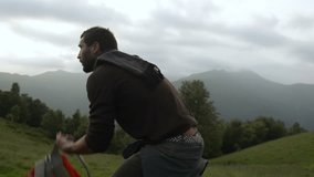 Young man with a red vintage backpack is walking outdoor on mountain path in overcast day - HD video footage