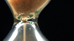 Super Close-up View of Sand Flowing Through an Hourglass on black background. Full HD 1920x1080 Video Clip