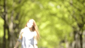 Young beautiful blonde girl in summer day is walking at town park - HD video footage