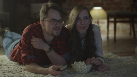 Young Happy Smiling Couple are Lying on the Floor and Watching TV and Eating Popcorn.
Shot on RED Cinema Camera in 4K (UHD).
ProRes codec  - Great for editing, color correction and grading.