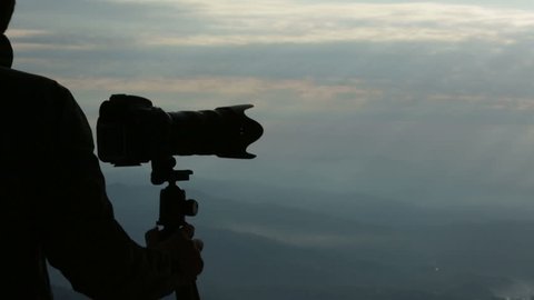 Young man photographer silhouette on Alps mountain top in nord italy in the early morning shoot with digital camera after enjoying the panorama outdoor - HD video footage: stockvideo