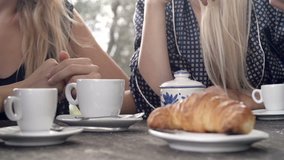 Close-up of italian breakfast with people: focus on man taking a croissant brioche. cup of coffee and cup of cappuccino on a summer sunny day morning in tuscany, italy - slow-motion HD video footage