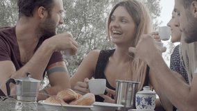 Group of four happy men and women friends smile, laugh and drink coffee during italian breakfast on a summer sunny day morning in tuscany, italy - slow-motion dolly HD video footage
