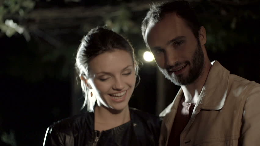 Young romantic man-woman couple in love smile, laugh using smartphone outdoor at night - slow-motion HD video footage | Shutterstock HD Video #8742463