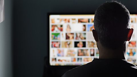 man watches surfing pornography site looking for virtual sex at night in a dark room,screen is out of focus uhd 4k,useful to represent internet easy porn accessibility and social issue