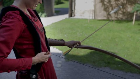 OTOCEC, SLOVENIA - JULY 2014: Turkish princess shoots with a bow. On this close up footage is a Turkish princess who is shooting with wooden bow in the middle of the castle on sunny day.