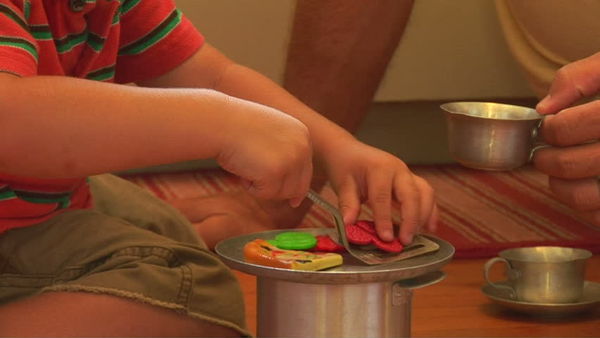 Father playing with toddler son on kitchen floor