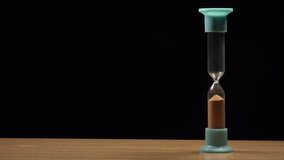 Male Hand Turning Hourglass on black background. 4K Ultra HD 3840x2160 Video Clip