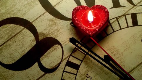 Love Stops Time-Red rose petals and a red heart candle that stops the seconds on old wooden clock.Minutes, seconds and hours are passing on wooden old vintage clock.