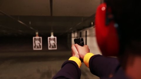 Male shoots handgun at target inside gun range. 1080p high definition.