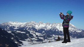 Young woman uses a smartphone to video a beautiful view in the mountains, Alps, Austria 