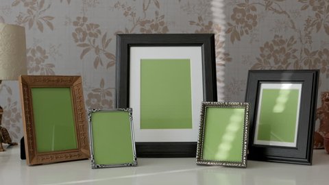 Group of Picture Frames with Green Screen on side table, tracking shot
