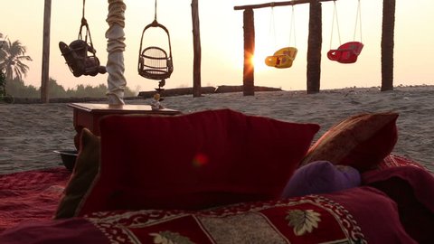 place of conducting Indian wedding ceremony with decorated sofa pillows for bride and groom and swing on the beach at dawn