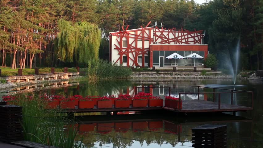 Scenery of modern, beautiful cottage with lake and fountain in a wood