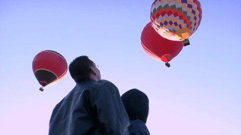 Couple looks up at hot-air balloons in sky. Stock Video