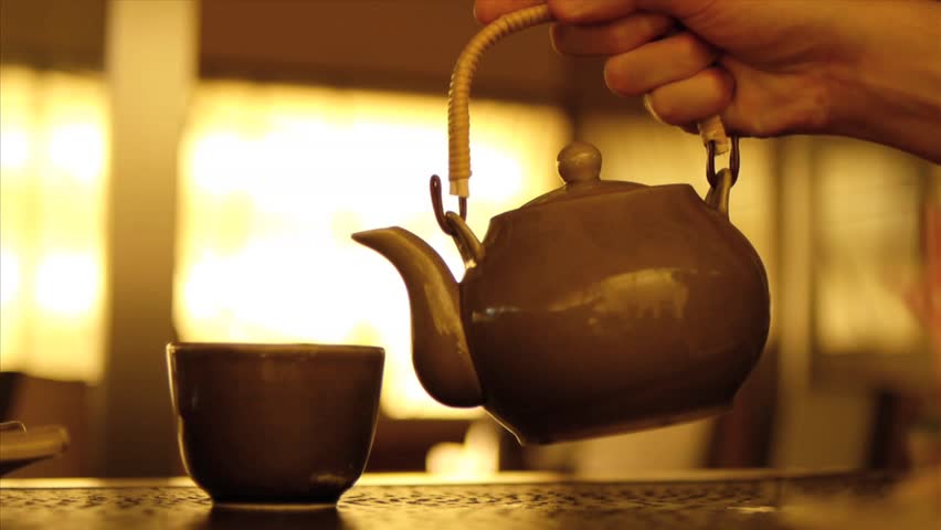 Hot water pouring from tea pot to tea cup