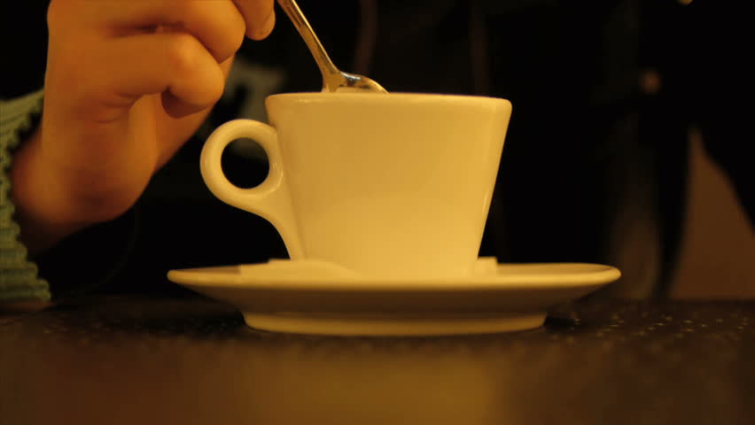Human hand stirring coffee in cup