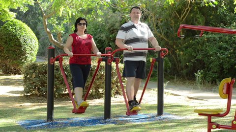 Happy family on air walker. Mature couple doing fitness training on air walker machine at the outdoor gym circuit