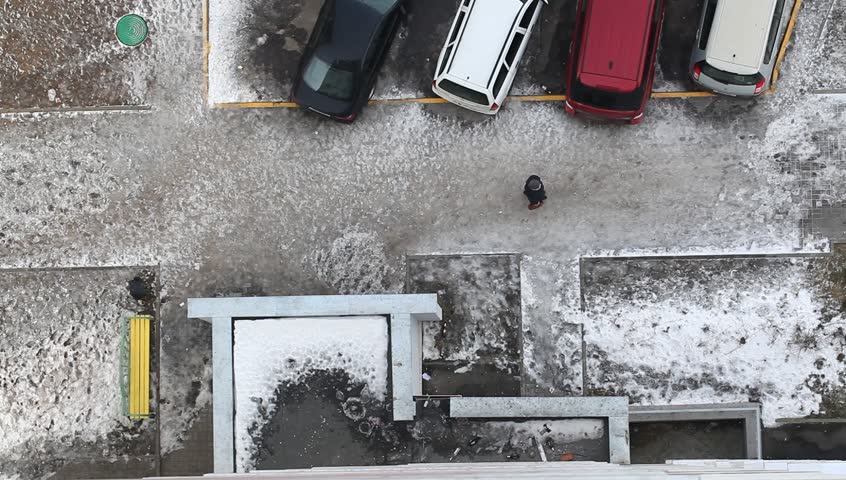 Iced pavement parking cars top view of a person goes through slippery winter street. Belarus,Minsk,February,01,2015