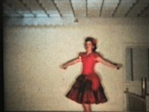 A pretty teenage girl in a red dress performs her dance routine complete with castanettes at her recital.
