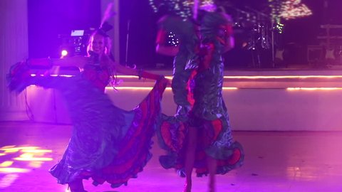 two young girls in cabaret costumes dance cancan in front of the stage at the catholic wedding party
