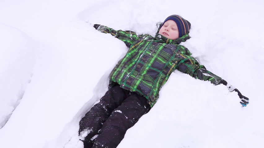 Little boy smiling and making a snow angel