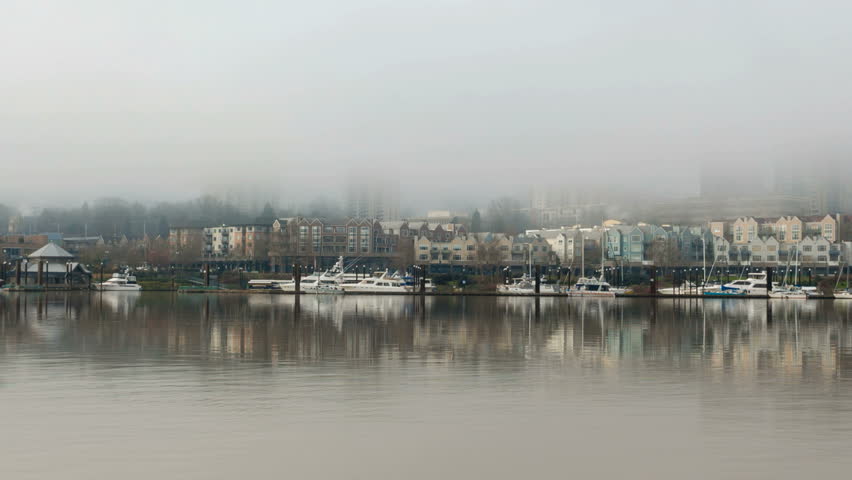 Time Lapse Movie of Moving Low Clouds and Fog Over Downtown Portland Oregon with Condominium Buildings Boats and Water Reflection along Willamette River One Early Misty Winter Morning 1080p