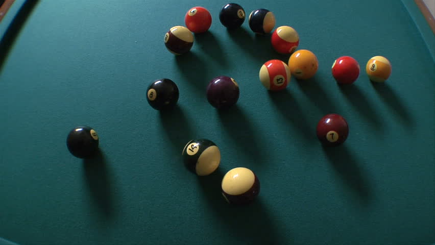 This is an overhead shot of billiards balls being racked and then breaking. shot