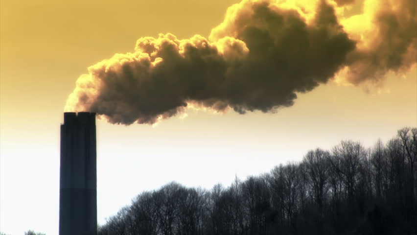 Smoke emerges from a tall smoke stack on an early morning.