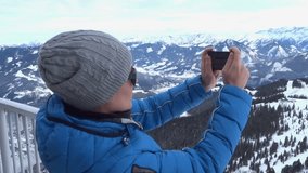 Young woman uses a smartphone to video a beautiful view in the mountains, Alps, Austria. Steadicam shot