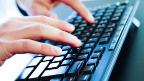 Close-up of a young man typing on a pc keyboard, technology business concept