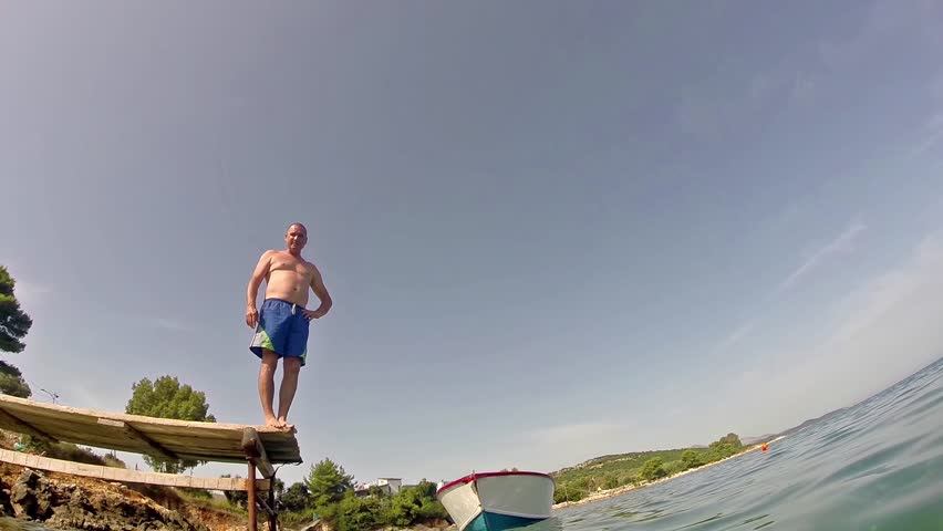 Men who jumps off dock on the lake, slow motion stock video