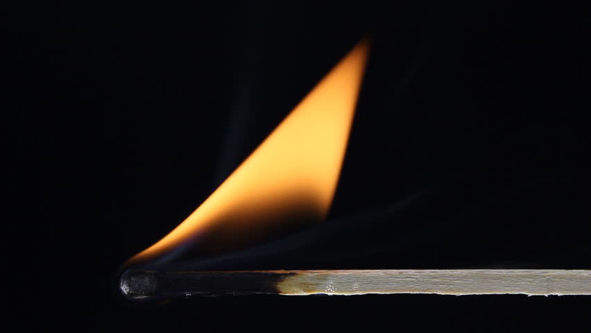 A wooden match close up catches on fire and burns, then is blown out, leaving