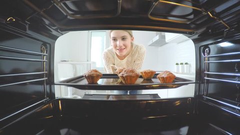 Cooking at home, Baking in the oven. Beautiful girl in her kitchen puts her cake into the oven 4K
