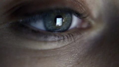Close up of girl's eye reading internet, with reflection of screen in her eye
