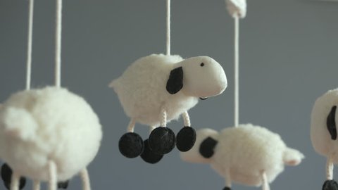 Lamb Nursery Mobile spinning above Baby Crib, Close-Up