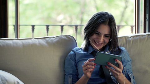 Happy, young businesswoman watching film on smartphone at home

