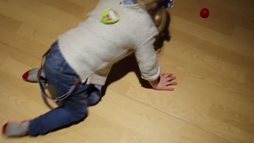 Top view of little girl catching small ball on floor in room 

