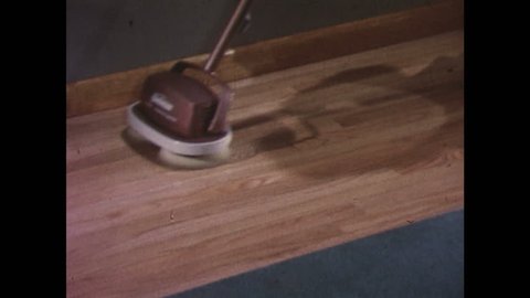 UNITED STATES 1960s: Floor polisher cleaning hardwood floor / Polisher cleaning baseboard / Polisher on linoleum floor / Polisher cleaning around chair leg.