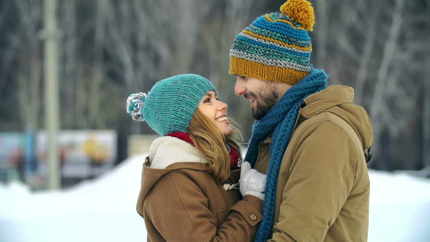 Close up of young couple cuddling standing in the middle of outdoor skating rink