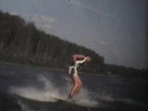 A teenage boy shows off his skill as he water skis on the lake in summer.