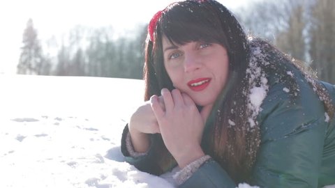 Beautiful brunette girl smiling lying on the snow