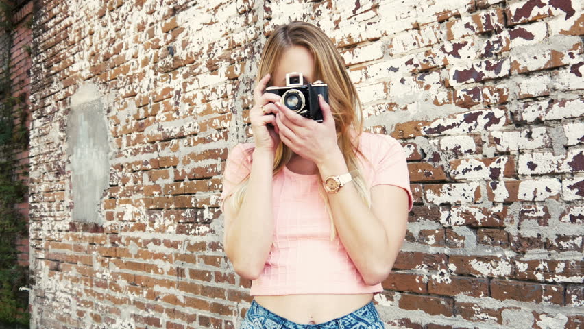 Hipster trendy girl with vintage camera on grunge wall