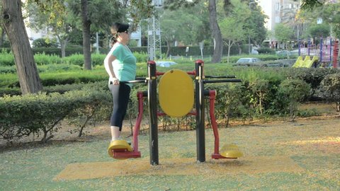 50 year old woman is enhancing body coordination and flexibility on surfboard station outdoor early in the morning